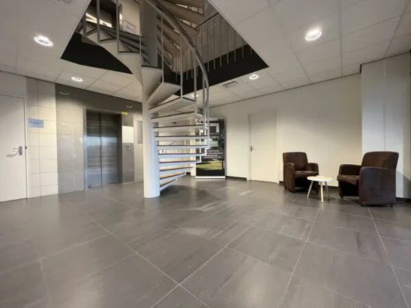 Moderne ontvangstruimte in kantoorpand in Leidse Rijn met wenteltrap, lift en zitgedeelte.